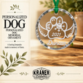 Personalized dog memorial ornament package by Kraner Customs, featuring a round clear glass ornament with a silver rim and a green hanging ribbon. The ornament is engraved with a dog silhouette, heart, snowflake, wings, the year 2021, and the name Duncan.